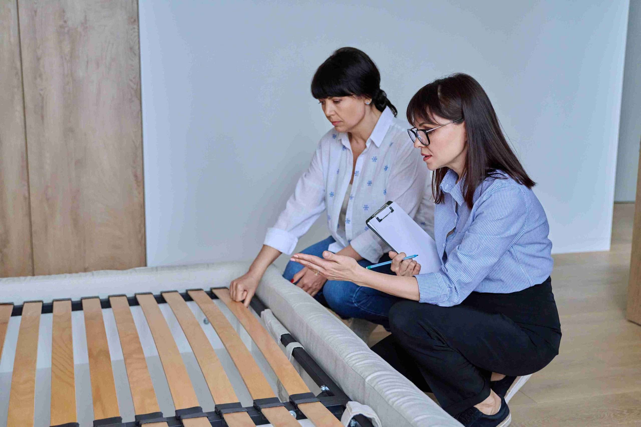 two people inspecting a slatted bed base